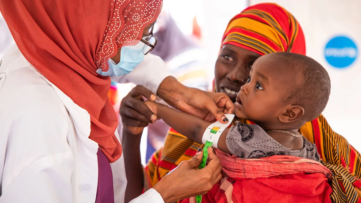 Un petit enfant reçoit un vaccin dans les bras de sa mère.