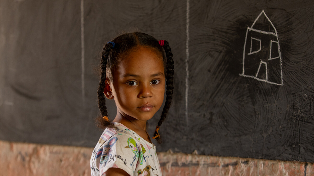 Ein kleines Mädchen aus dem Sudan steht vor einer Tafel.