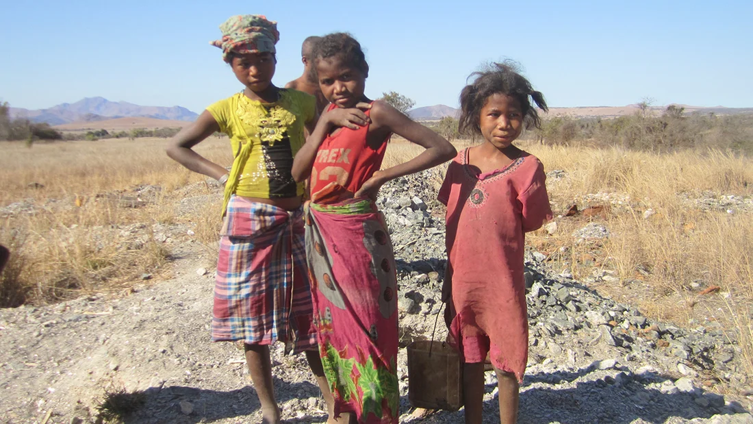 Trois enfants se tiennent dans un champ.