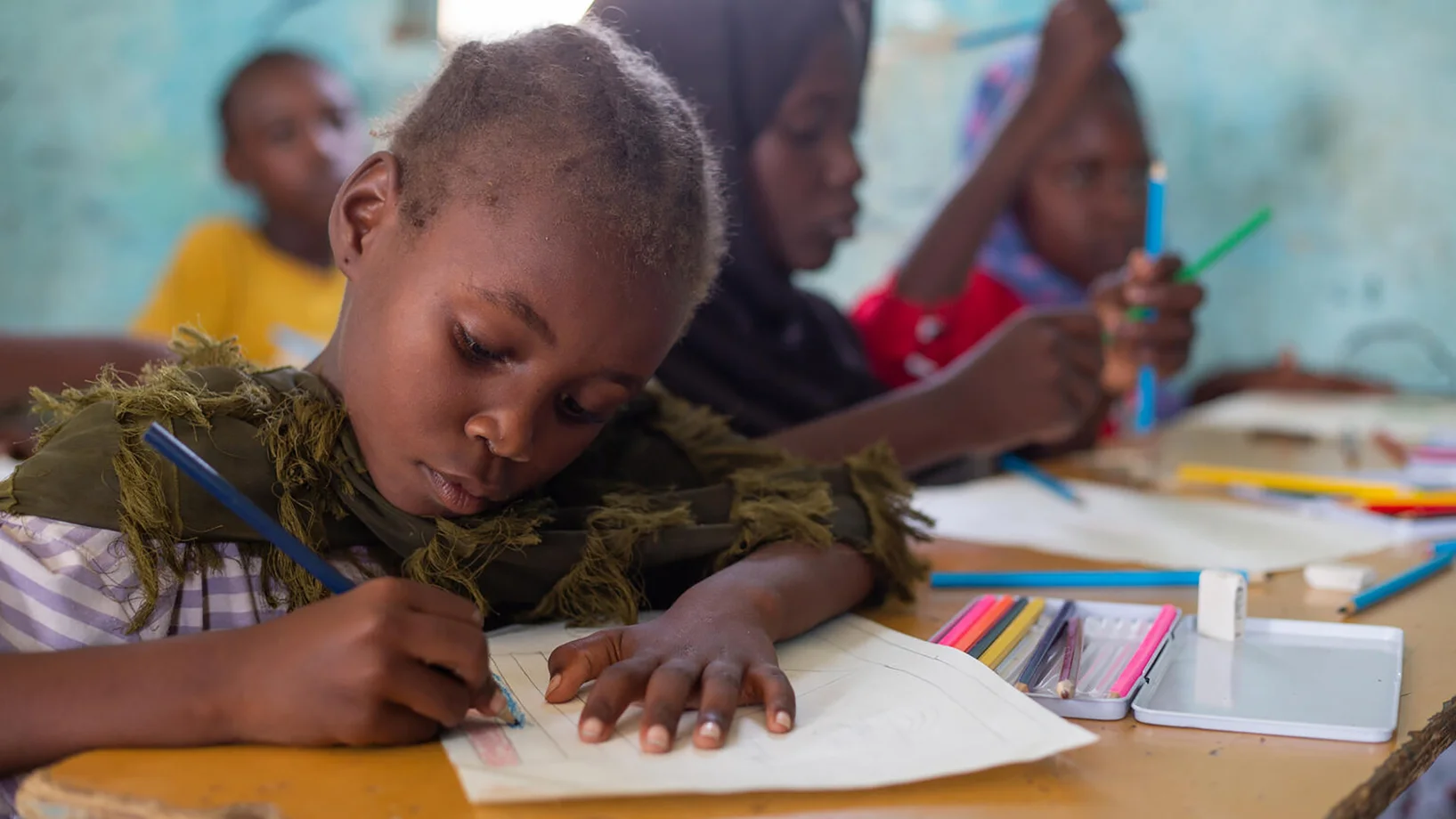 Ein Mädchen im Sudan schreibt eifrig im Schulunterricht mit.