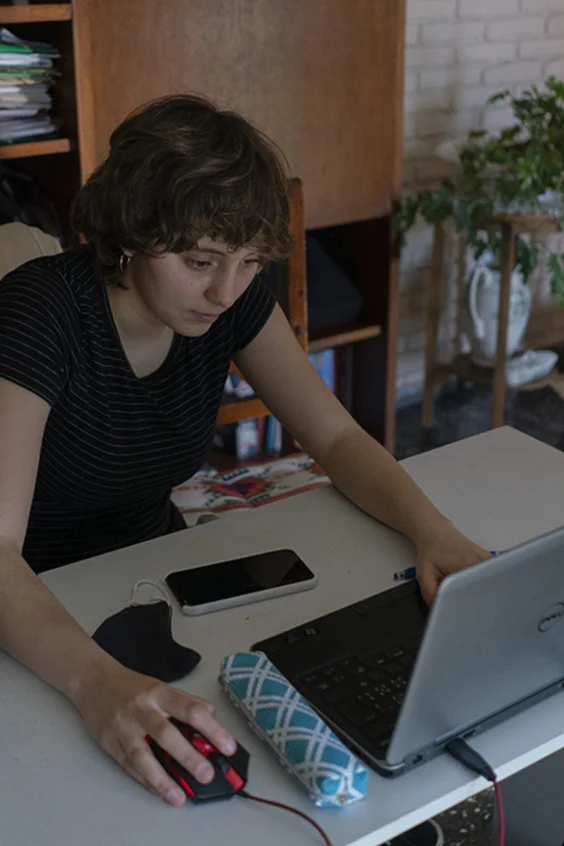 Frau sitzt am Schreibtisch und schaut auf einen Computer.